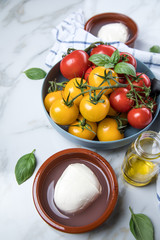 Rote und gelbe Tomaten mit Mozzarella, Basilikum und Olivenöl auf Marmor Hintergrund