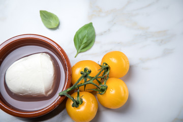 Gelbe Tomaten mit Mozzarella und Basilikum auf Marmor Hintergrund 