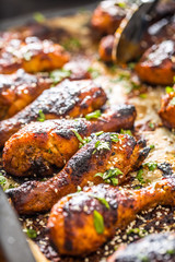 Grilled hicken legs BBQ with spices herbs and sesame on baked paper. Roasted poultry meal in roaster dish