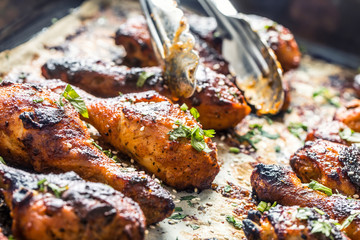 Grilled hicken legs BBQ with spices herbs and sesame on baked paper. Roasted poultry meal in roaster dish