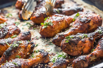 Grilled hicken legs BBQ with spices herbs and sesame on baked paper. Roasted poultry meal in roaster dish