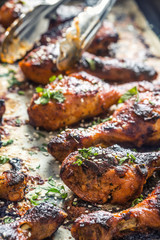 Grilled hicken legs BBQ with spices herbs and sesame on baked paper. Roasted poultry meal in roaster dish