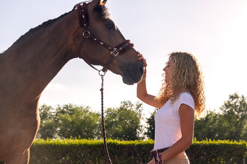 blonde girl stroking a horse