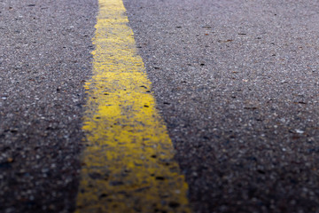 Obraz premium Yellow solid line, grunge single road marking on asphalt, background with copy space