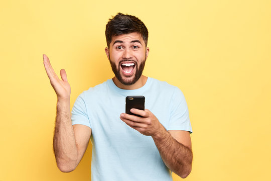 surprised emotional man with wide opened mouth screaming, rejoicing at good message, news. guy has recieved sms that he has won the lottery. luck , success, happiness