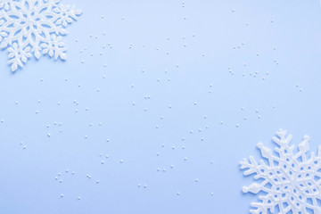 Christmas and new year concept. White snowflakes on blue background. Top view, flat lay composition, frame, layout. Copy space for text or design. 