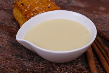 Condenced milk in the bowl with sinnamon and pastry