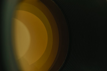 Beautiful camera lens with  yellow light reflection of glass on a black background..