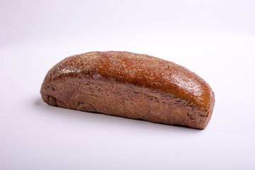 Long brown bread on a white background with crispy cumin and spices