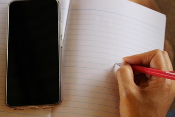 The girl is writing a message on brown paper, in low light, taking a blurred picture