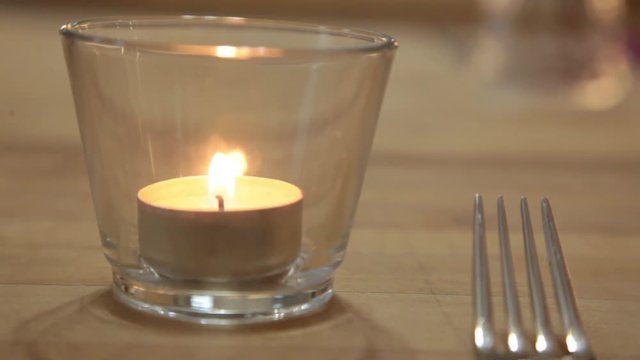 magic candle fire into a glass on table near the fork