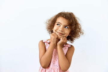 Fototapeta premium Dreamy,pleased, thinking emotion . Wish concept. Little African American girl face portrait on white backgound.