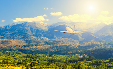 Fototapeta na wymiar rear view plane flying over beautiful valley , mountains, clouds and sun on background