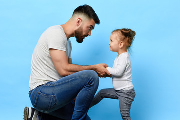 caring father and little obedient daughter who listens to the instruction of parent on blue isolated background. daddy making an observation to kid. dad asking daughter to behave well