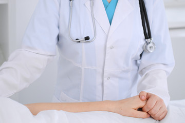 Female doctor reassuring her patient in hospital ward. Medicine and health care