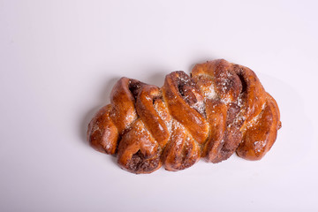 Baking with poppy seeds. Poppy roll in the form of a pigtail. Golden baked roll on a white background