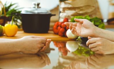 Closeup of human hands discussing something while cooking in kitchen. Women talking about menu. Family dinner, friendship and lifestyle concept