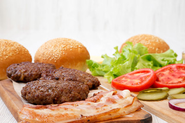 Burger ingredients on a white wooden surface, side view. Close-up.