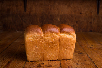 Baked bread on a brown background. Loaf of fresh bread on a wooden table
