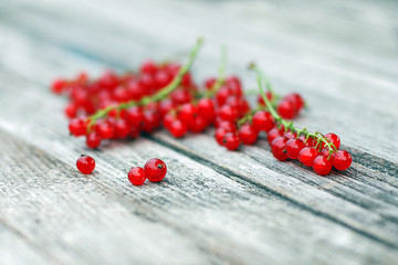 Red currant berries lying on old gray wooden surface, selective focus, shallow depth of field