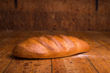 Baked bread on a brown background. Loaf of fresh bread on a wooden table