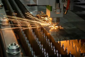 The fiber laser cutting machine cutting the sheet metal plate with the sparking light. The sheet...