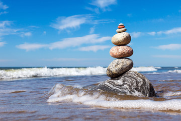 Rock zen pyramid of colorful pebbles standing in the water on the background of the sea