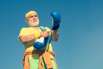 Senior men fighting poses. Senior sportive man in boxing stance doing exercises with boxing gloves....
