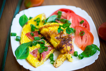 fried omelet from homemade organic eggs with tomatoes and green onions
