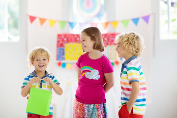 Child opening birthday present. Kid at party.