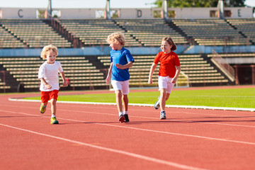 Child running in stadium. Kids run. Healthy sport.