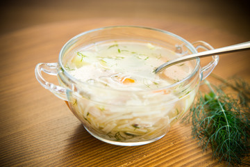 Chicken soup with noodles and carrot in white bowl.