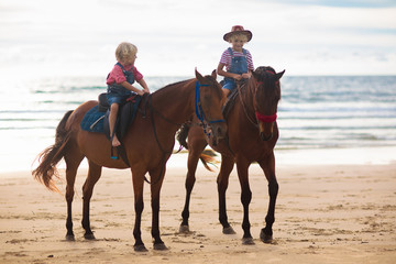 Kids riding horse on beach. Children ride horses.