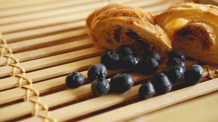 Delicious breakfast with fresh croissant and blueberry on wooden background