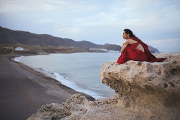 Young brunette woman dancer resting in a rock near the beach
