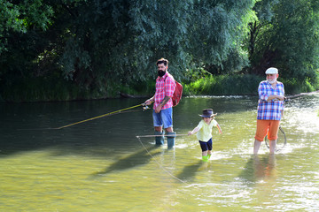 Happy grandfather, father and grandson with fishing rods on river berth. Fly fishing. Little boy on...