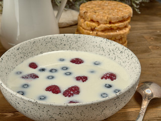 Breakfast.Corn sticks ,and cereal with milk.Raspberries and blueberries.On the background colors