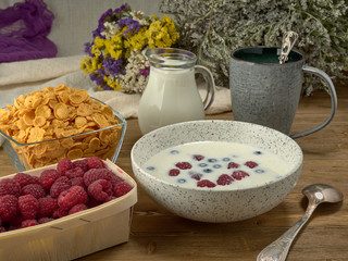 Breakfast.Corn sticks ,and cereal with milk.Raspberries and blueberries.On the background colors