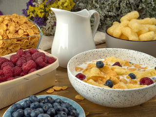 Breakfast.Corn sticks ,and cereal with milk.Raspberries and blueberries.On the background colors