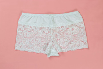 Women's white lacy panties on pink background