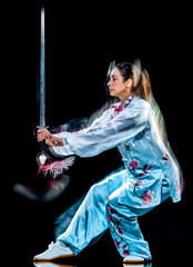 one chinese woman partacticing Tai Chi Chuan Tadjiquan posture studio shot isolated on black background with light painting effect