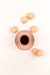 Teatime, Pink cup of tea and scattered biscuits on white table. top view. Copy space