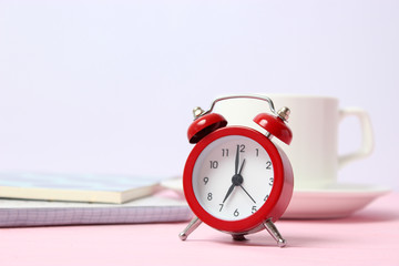 alarm clock on a colored background, a cup of coffee and stationery