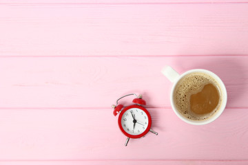 alarm clock and coffee on a colored background top view.