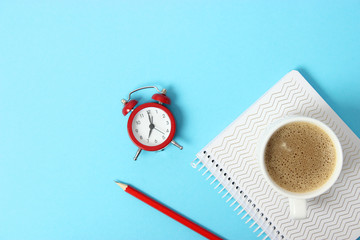 alarm clock and coffee on a colored background top view.