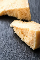 Parmesan cheese on black stone background. Top view, copy space.