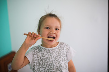 child brushes her teeth with bamboo toothbrush
