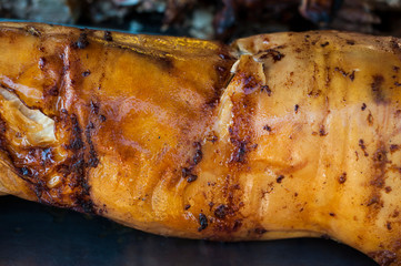 Traditionally suckling pig on a rotating spit with fire and smoke