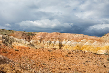 Red mountains on a sunny day against the backdrop of thunderclouds in the valley of Mars in the Altai. Nature of Siberia
