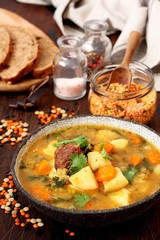 Homemade lentil soup with bread and parsley on wooden table